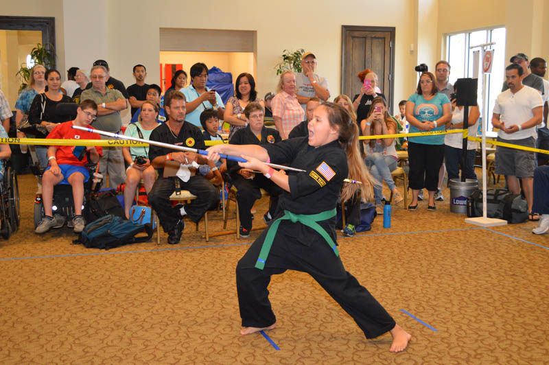young girl holding a staff performs in a martial arts tournament